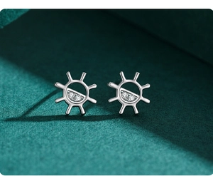 Macro shot of silver sunburst earrings with pavé crystals on dark green velvet background
