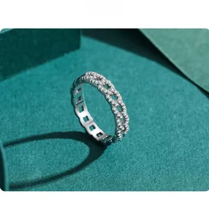 Macro shot of silver chain link ring with sparkling cubic zirconia on green surface