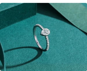Close-up of a pear-cut teardrop cubic zirconia ring with silver band in a green setting