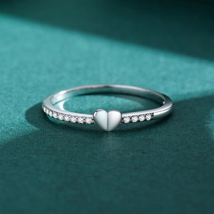 Minimalist S925 sterling silver heart ring with zircon stones on a dark green surface