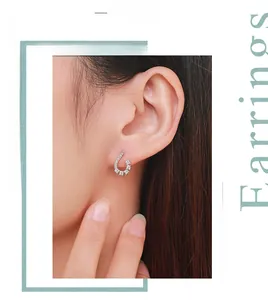 Close-up of S-shaped silver earring with paved zircons shown on a model's ear lobe