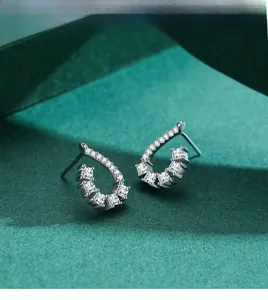 Macro shot of silver teardrop earrings with pave-set cubic zirconia on green background