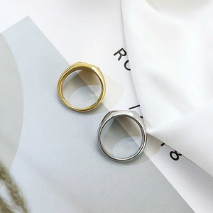 Top view of gold and silver polished oval signet rings on a stylish magazine background