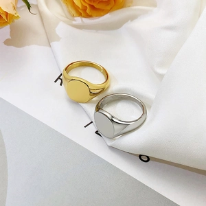 Detail of minimalist gold and silver oval signet rings resting on white silk fabric