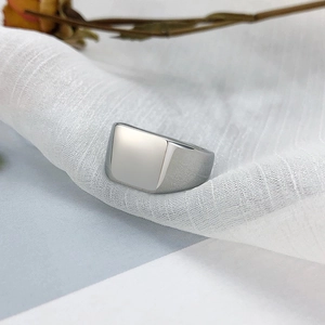 Gros plan d'une bague chevalière carrée en acier inoxydable poli sur tissu blanc