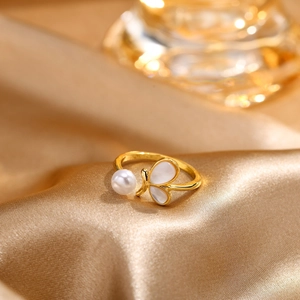 Detail of adjustable gold ring with white pearl and shell-inlaid butterfly on satin