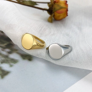Close-up of gold and silver polished stainless steel signet rings on white fabric