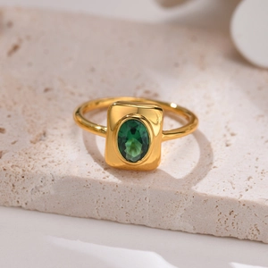 Detailed macro view of a vintage gold ring with an oval green zircon on stone background