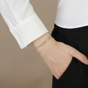 Classic gold stainless steel tennis bracelet with round cubic zirconia on a model's wrist