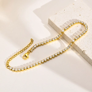 Detail of 18K gold tennis bracelet with cubic zirconia on a white textured stone