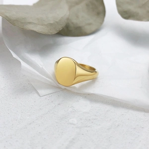 Macro detail of high-polished gold oval signet ring on elegant textured background