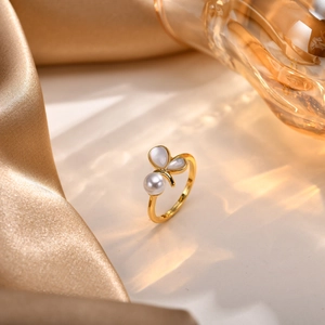Close-up of golden butterfly ring with pearl accents on a luxury silk background