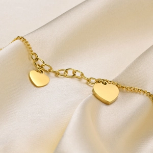 Close-up of a polished gold heart pendant resting on elegant beige silk fabric