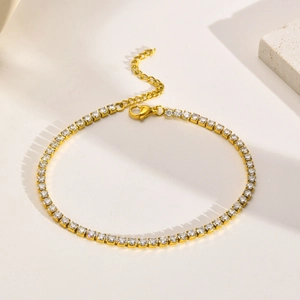 Macro view of gold tennis anklet with claw-set white zircons and adjustable lobster clasp