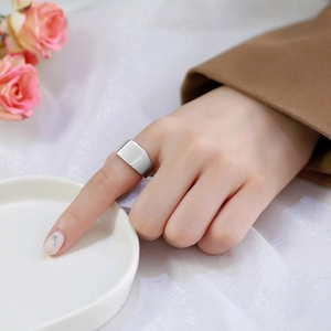 Bague carrée argentée polie sur la main du mannequin avec fond floral élégant