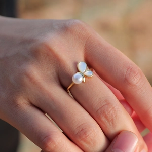 Elegant gold butterfly ring with white pearl and shell wings worn on a finger