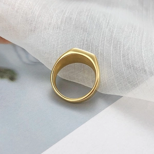 Détail de la bague chevalière carrée en métal doré poli avec une surface supérieure plane