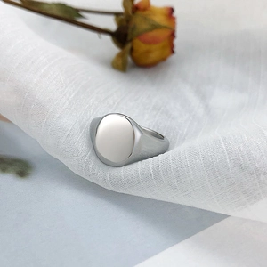 Macro view of minimalist oval flat top stainless steel ring on white textured fabric