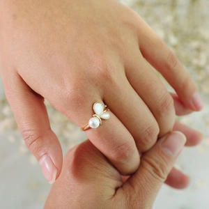 Close-up of golden butterfly ring with white shell wings and pearl worn on finger