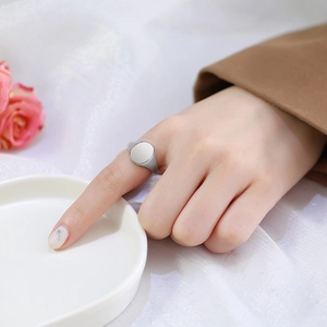 Close-up of minimalist silver signet ring with a smooth round face on a female hand