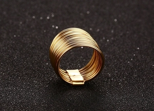 Macro shot of minimalist gold layered coil ring showing texture on a dark grey surface