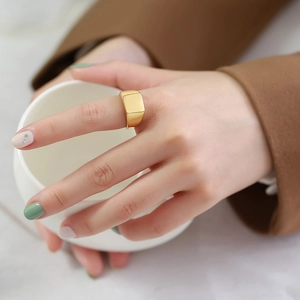 Chevalière carrée dorée polie au doigt avec un design minimaliste en métal élégant