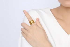 Detail shot of a multi-layer stacked gold ring worn by a model in a minimalist setting