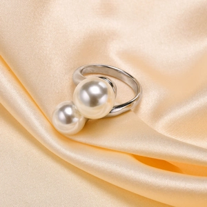Detailed close-up of a double pearl open ring on elegant champagne silk fabric background