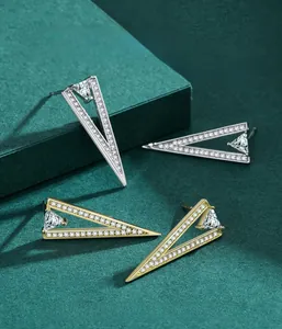 Macro detail of geometric silver and gold triangle earrings with inlaid cubic zirconia