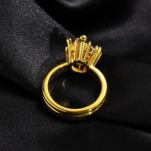 Close-up of golden crown ring with large zircon stone on elegant black silk background