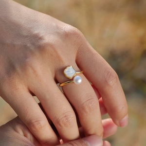Elegant gold open ring featuring a white pearl and shell detail on woman's finger