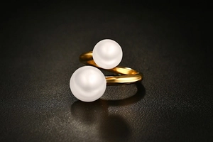 Detail view of a 3mm gold titanium steel open ring featuring two white pearls on black background