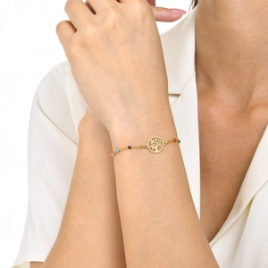 Detail of gold tree of life bracelet with colorful beads on a model's wrist