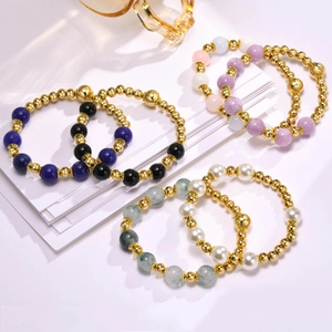 Detailed view of layered gold-plated bracelets with pearls and natural stone beads