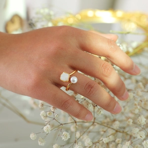 Detail of adjustable gold ring featuring a white pearl and square shell inlay on hand