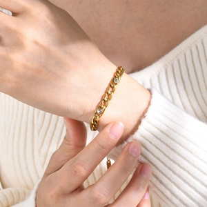 Gold stainless steel NK link bracelet with three white zircons on a female wrist