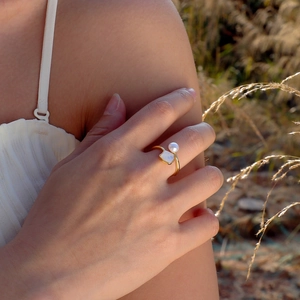Close-up of golden pearl ring with square seashell stone in warm sunset lighting
