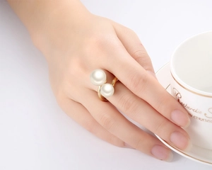 Detail of elegant gold-tone wrap ring featuring two white pearls on a model's hand
