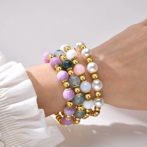 Stacked beaded bracelets with natural stones, pearls and gold beads on a model wrist