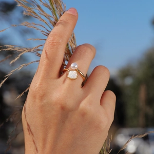 Detail of adjustable gold ring featuring a round faux pearl and square shell element