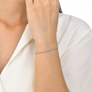 Close-up of minimalist silver snake chain bracelet on wrist with elegant white blouse