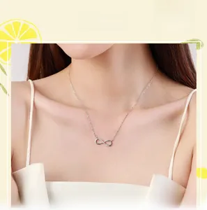 Close-up of infinity symbol pendant necklace with diamonds on a female model