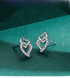Detailed view of s925 silver double heart stud earrings with cubic zirconia on green velvet