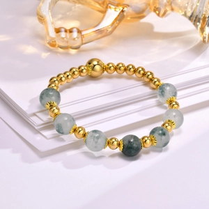 Detail of beaded bracelet with gold metal spheres and green patterned natural stone beads