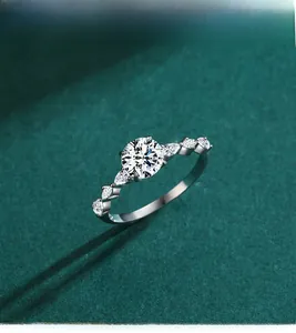 Top view of a 925 silver ring with 1 carat round moissanite on a dark green velvet background