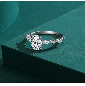 Macro detail of oval cut faux diamond ring with pear side stones on green podium