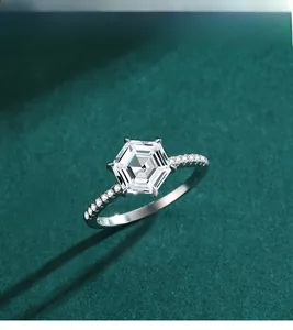 Vista macro di un anello con diamante esagonale e pietre laterali su velluto verde
