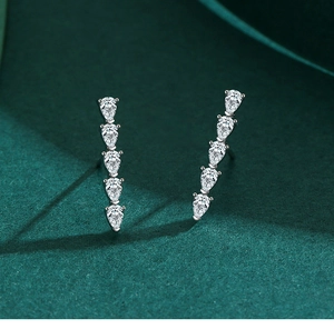 Gros plan de boucles d'oreilles en argent S925 avec cinq zircons sur velours vert
