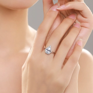 Bague luxueuse en argent S925 avec diamant poire et halo portée sur un doigt