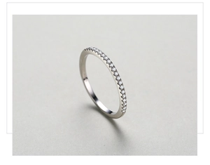 Close-up of a minimalist S925 sterling silver half-eternity ring with clear pavé zircons